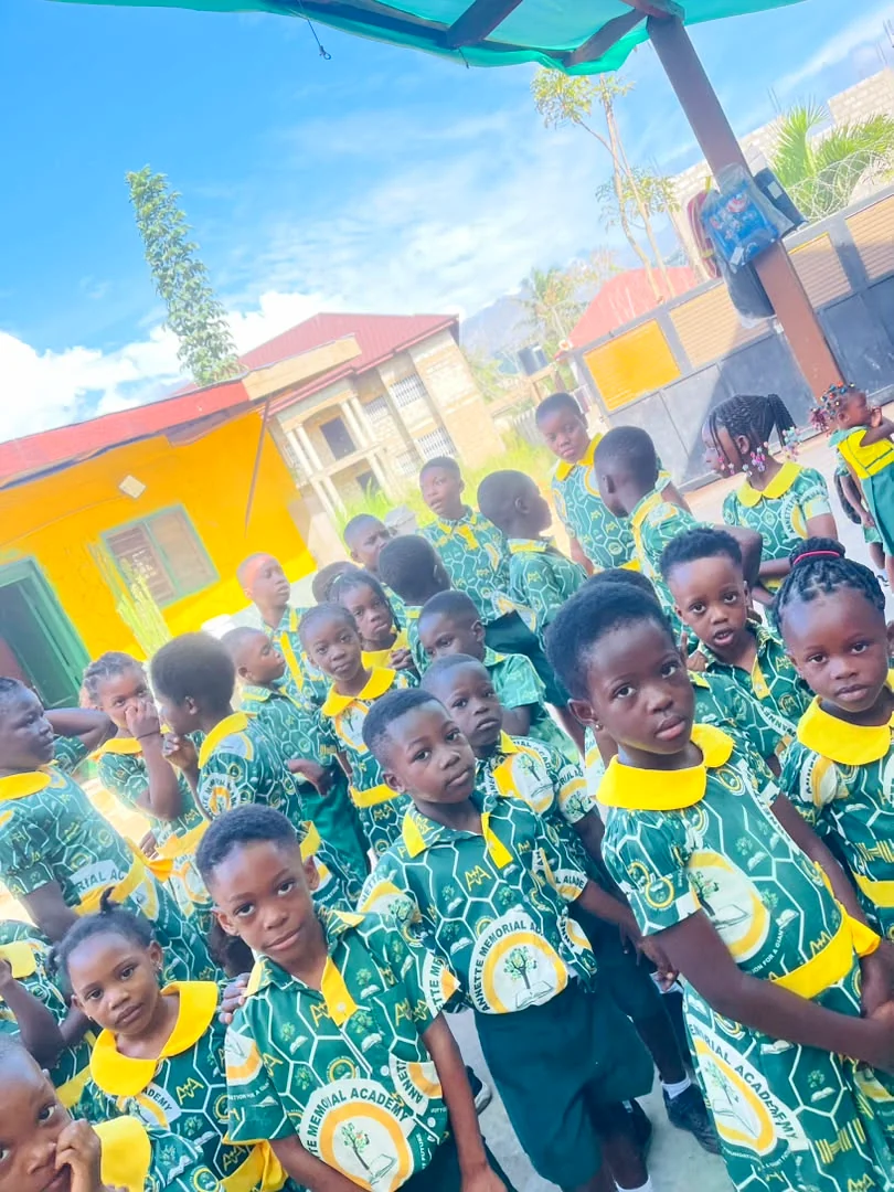 ASMA pupils in green and gold uniforms beneath the school canopy