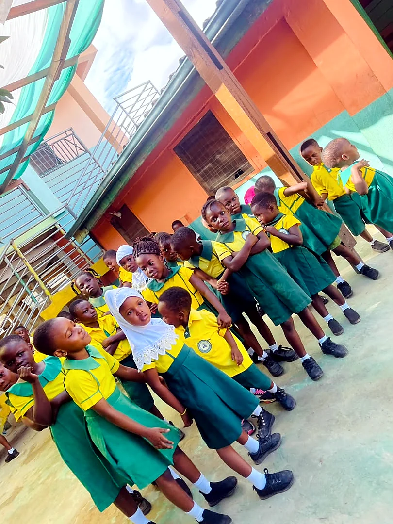 Young ASMA learners standing together in green and yellow uniforms