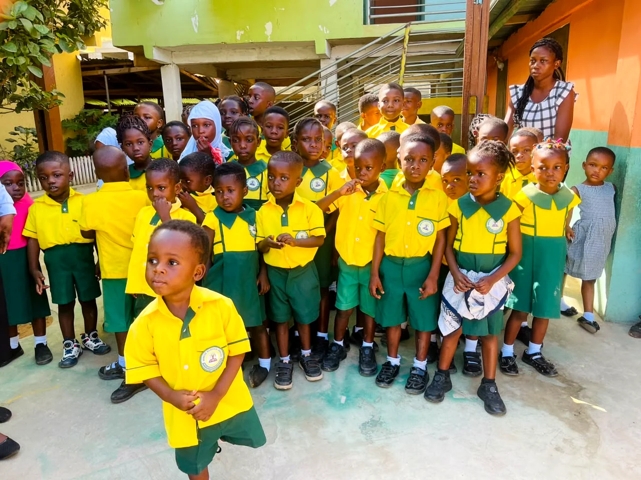 Young ASMA pupils standing together in yellow and green uniforms